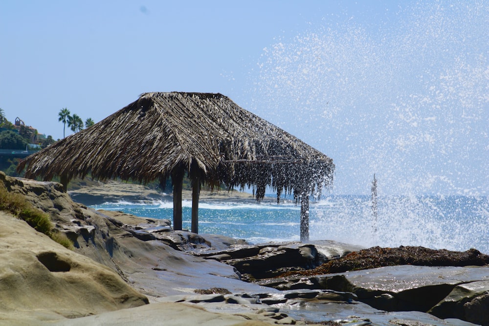 Una cabaña con techo de paja en una playa rocosa junto al océano