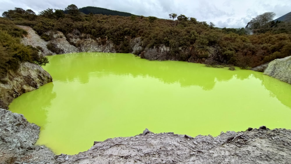 a green lake surrounded by rocks and trees