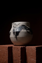 raku vase sitting on top of a brick wall
