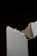 A close-up view of a broken piece of white plaster or ceramic material with rough, jagged edges against a dark background.