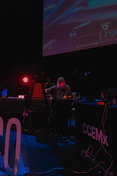 A cinematic, minimalist shot of DJ rojosónico performing live in an industrial venue with moody lighting.