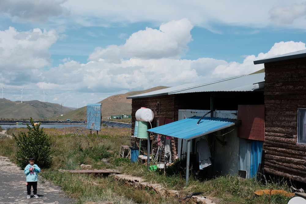 un petit enfant debout devant une cabane