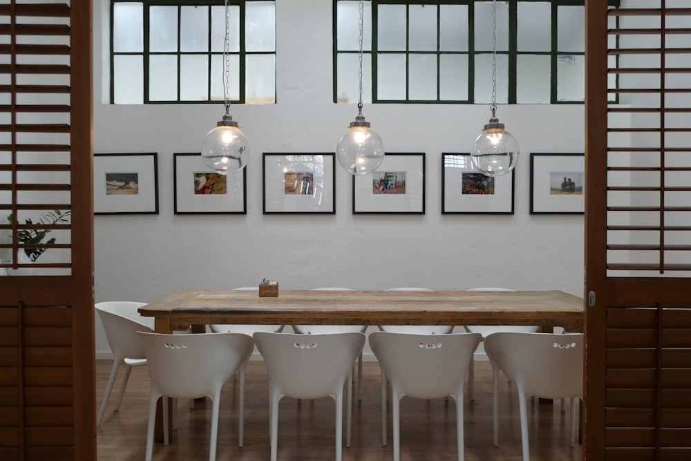 a wooden table surrounded by white chairs in a room