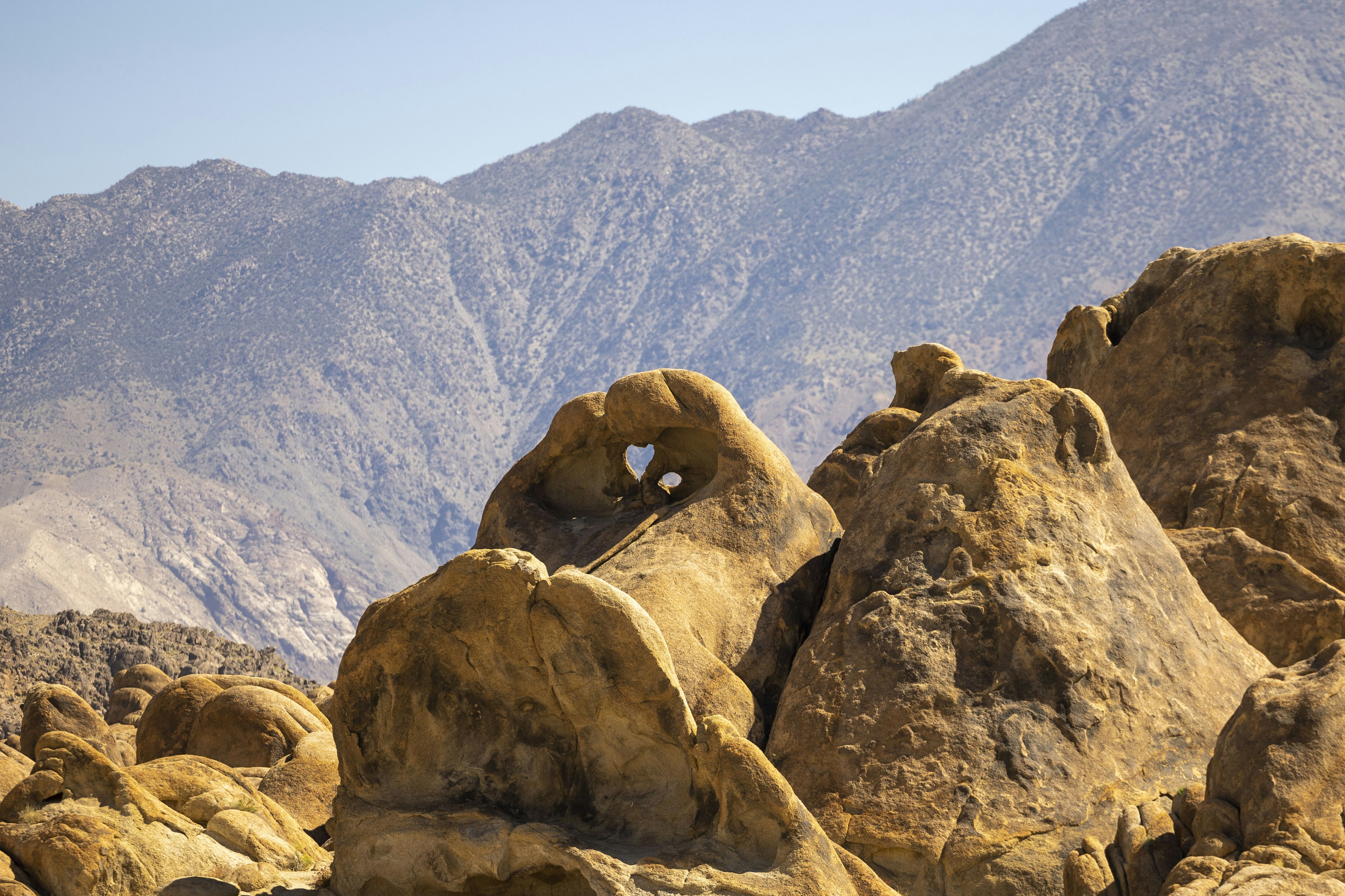 A large rock formation with mountains in the background
