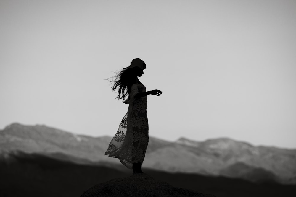 a woman standing on top of a rock