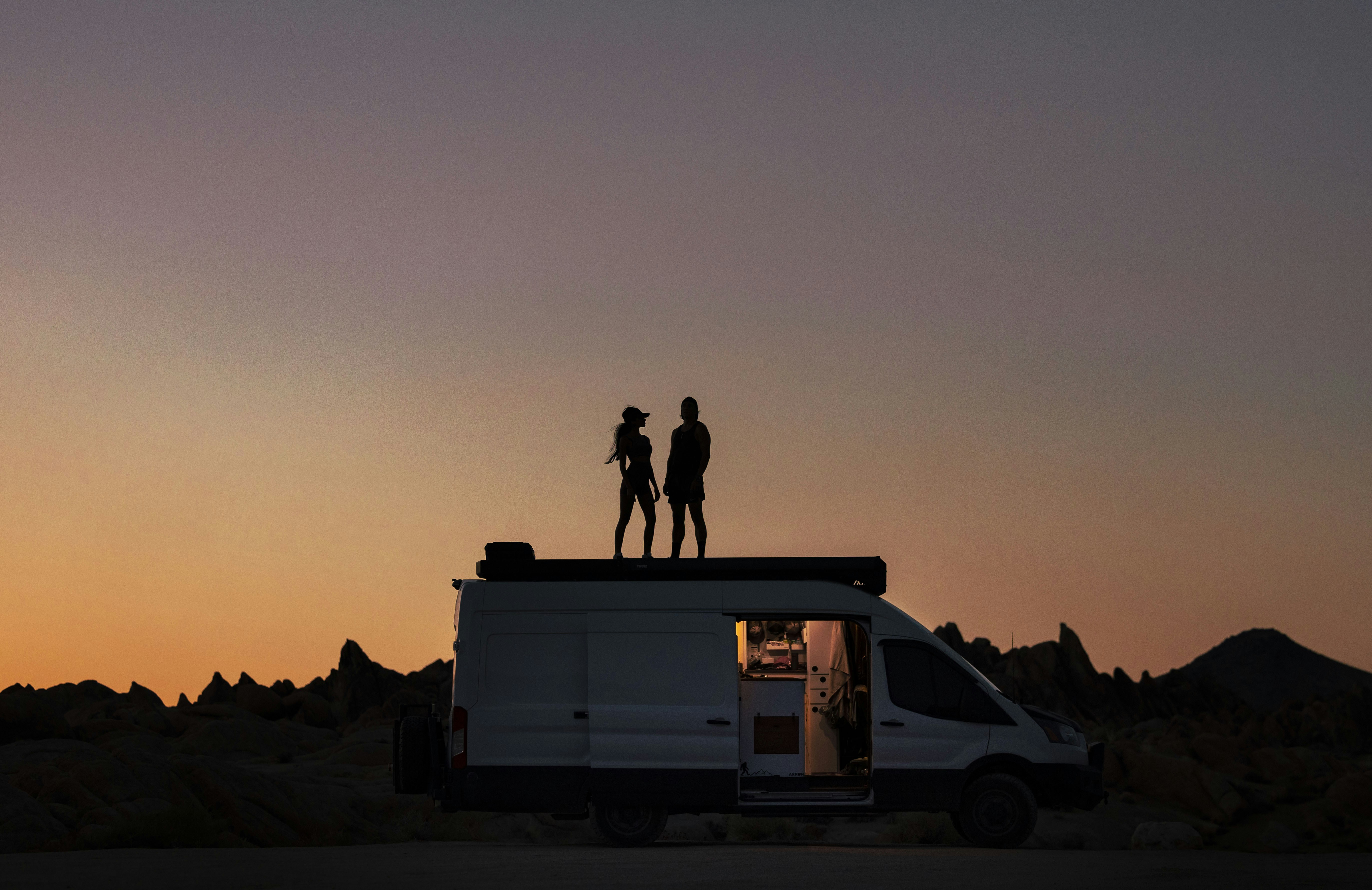 a couple of people standing on top of a van