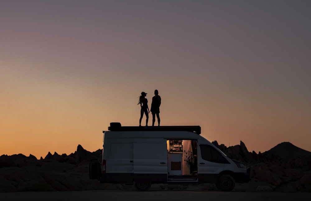 a couple of people standing on top of a van