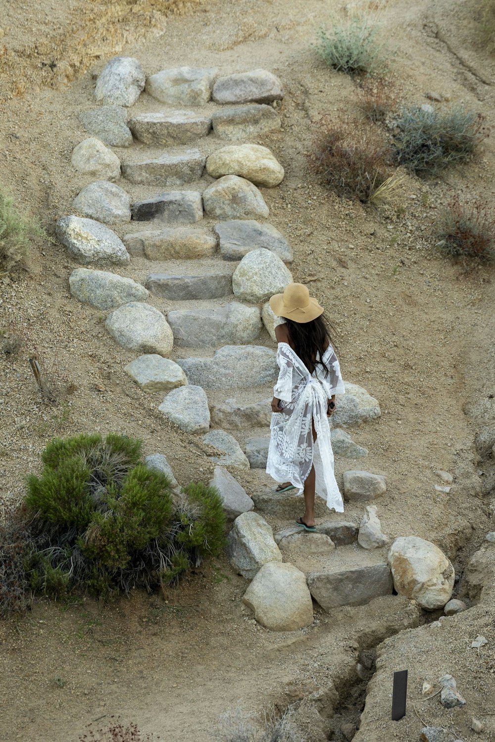 a woman in a hat walking up a set of stairs