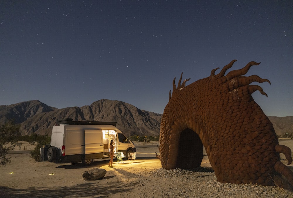 a camper trailer parked next to a dragon like structure