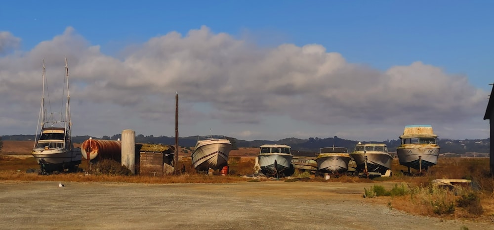 a group of boats sitting on top of a dry grass field