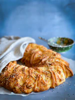 A close-up of freshly baked cozonac with a golden crust cooling on a wooden table.