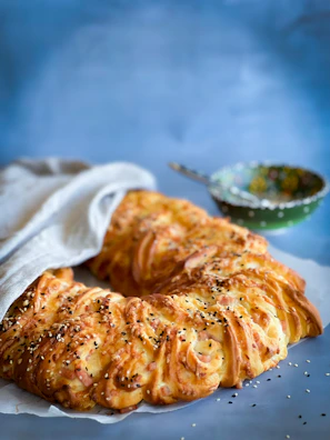 A close-up of freshly baked cozonac with a golden crust cooling on a wooden table.