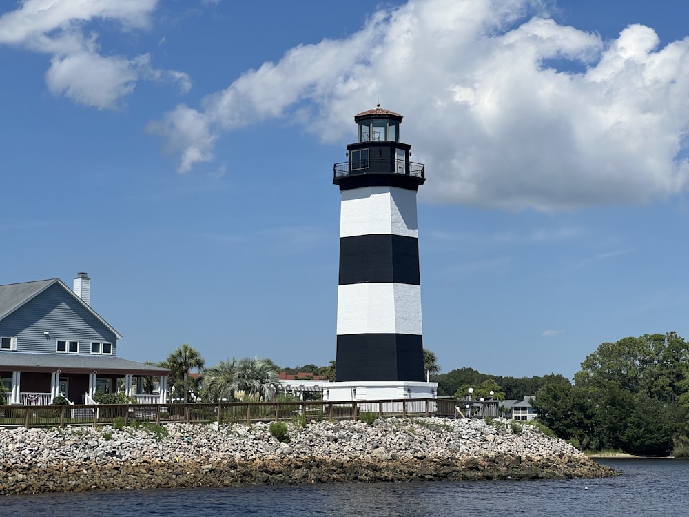 a black and white lighthouse sitting on top of a body of water