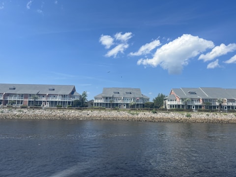 A row of modern semi-detached homes with large windows overlooking green hills under a clear sky.
