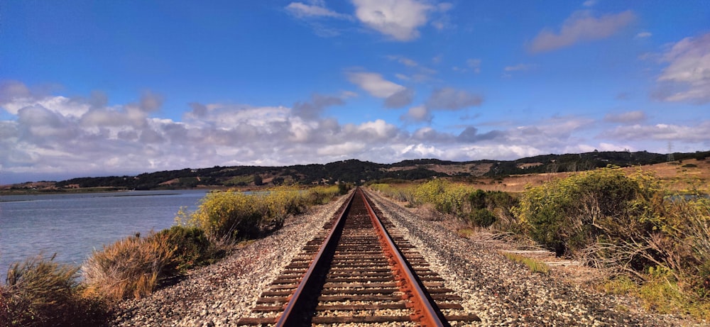 a train track with a body of water in the background