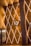An elegant, geometric wall display with golden lighting and triangular patterns features prominently. Intricate, illuminated lines criss-cross the surface, creating a diamond-like pattern. A central abstract logo or emblem stands out amidst the design. A large column is visible on the right, and glass doors on the left reveal a glimpse of a decorated interior.