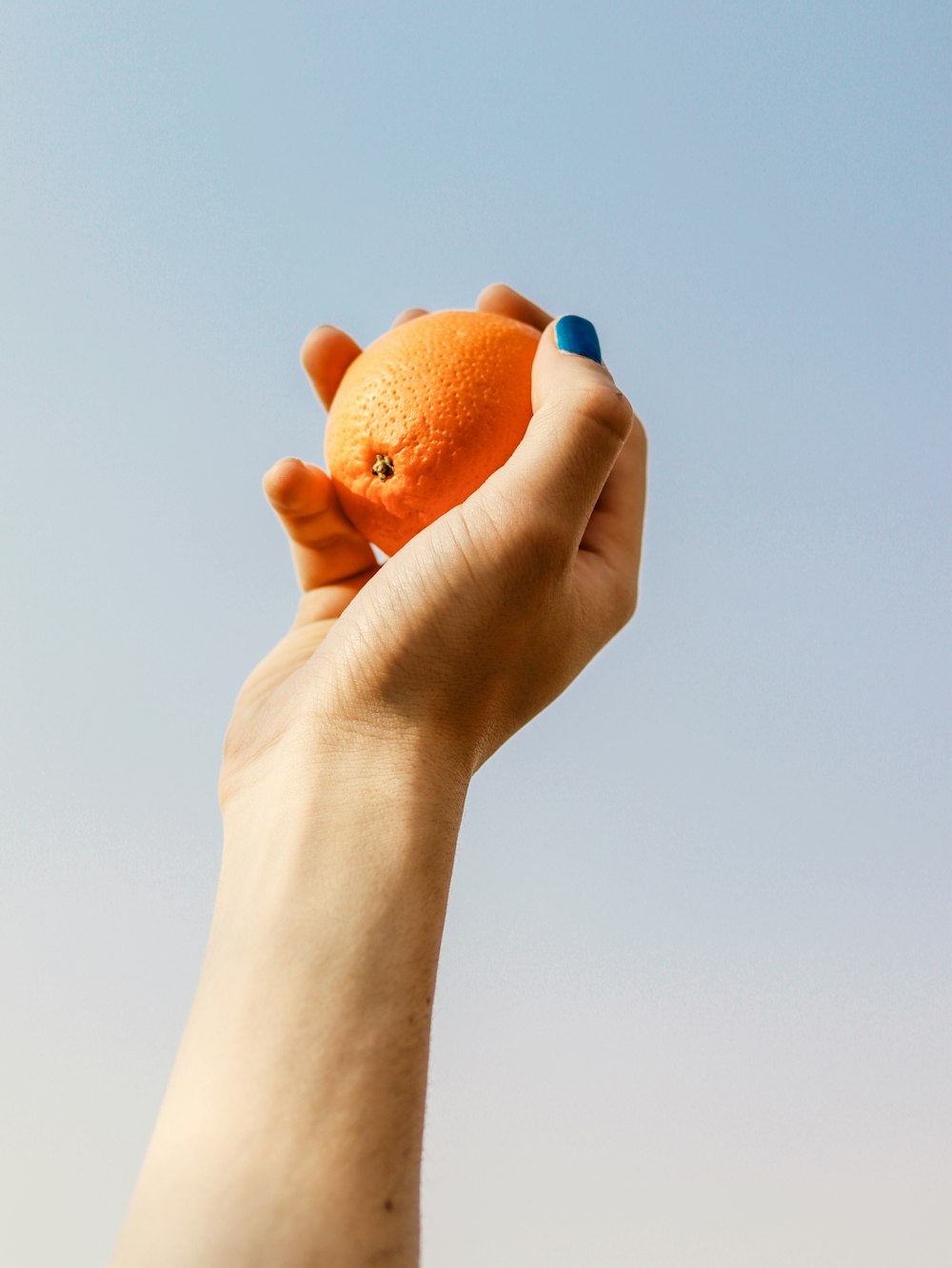 a person holding an orange up in the air