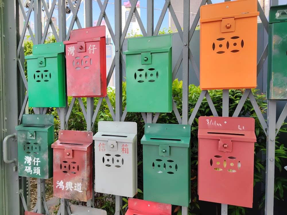 a bunch of mail boxes are hanging on a fence