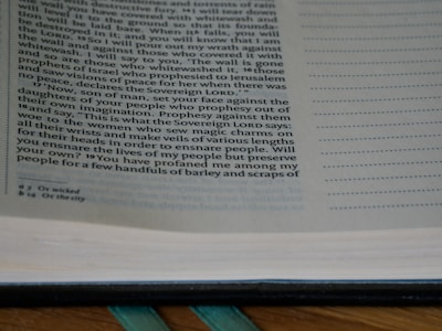 A close-up of a page from an open book, containing text with a religious theme. The text is printed in a serif font and includes numbered verses. The page has annotations or footnotes at the bottom.