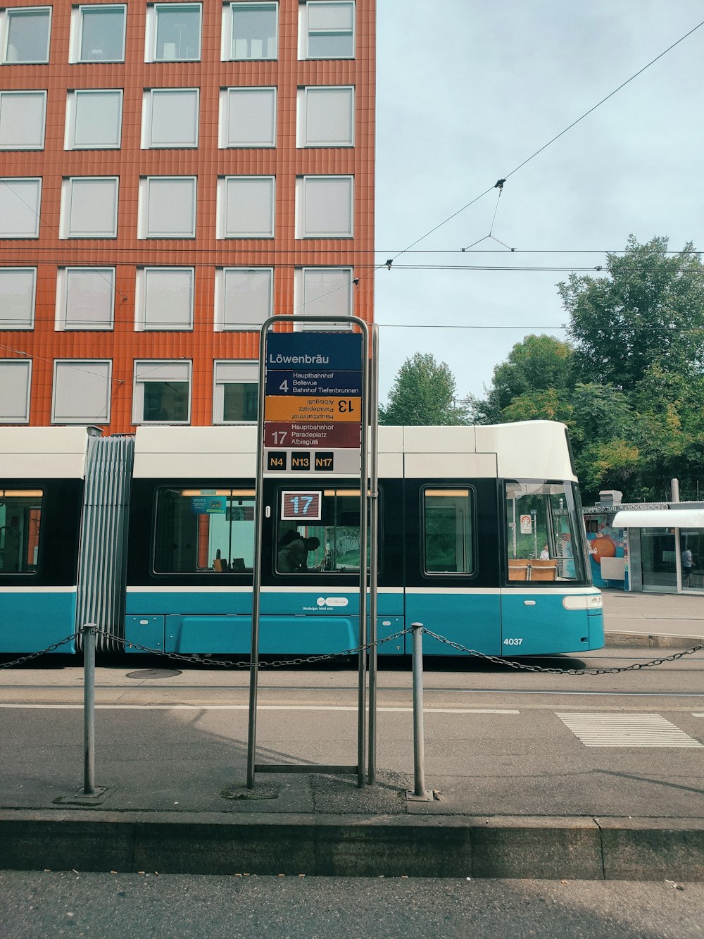 a blue and white train traveling past a tall building