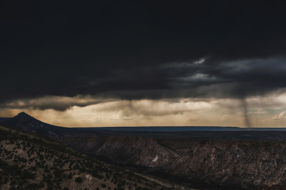 a dark sky with a few clouds above a mountain