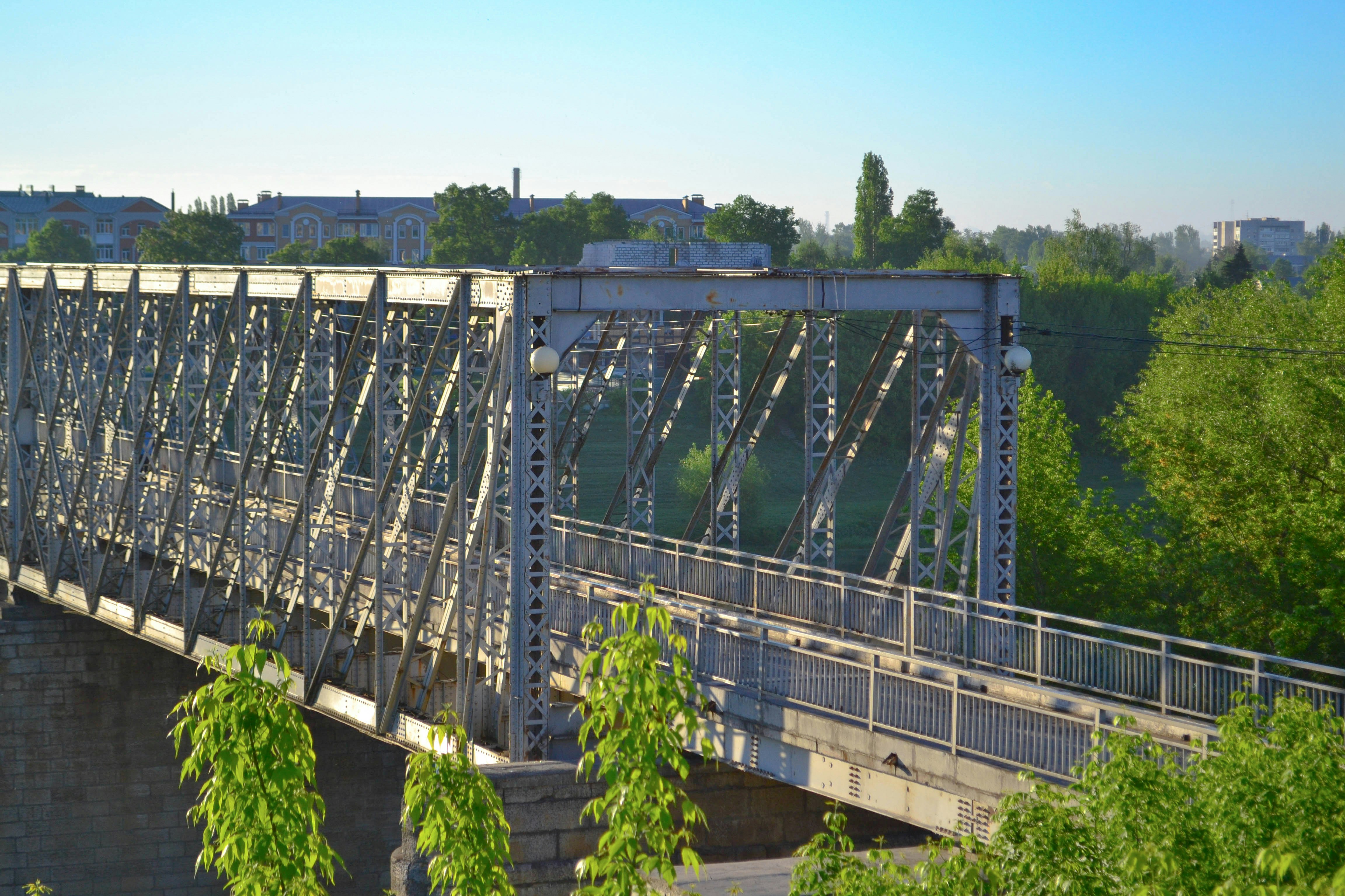 a bridge over a river with trees and buildings in the background