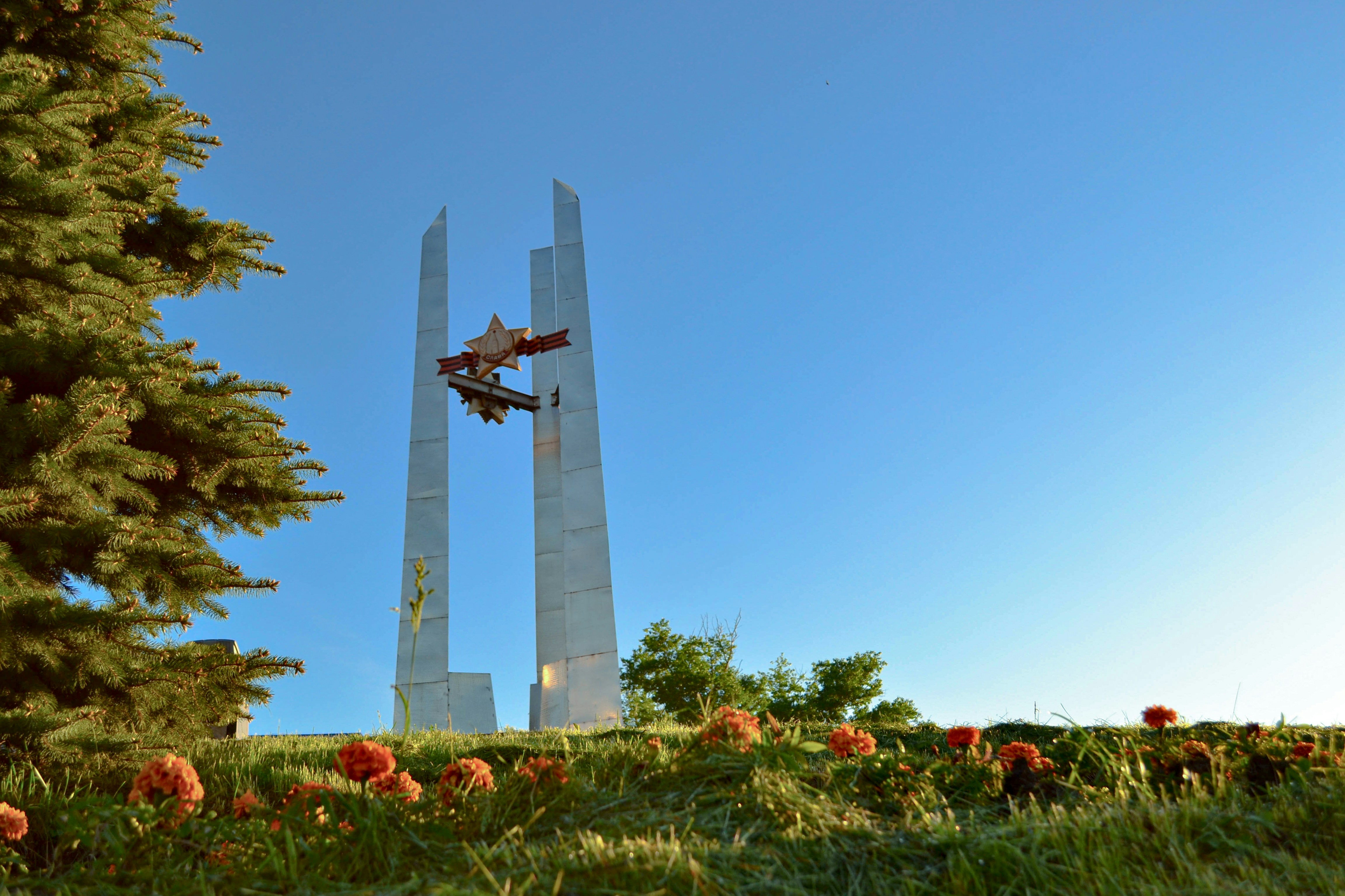 a small plane flying over a monument in a field