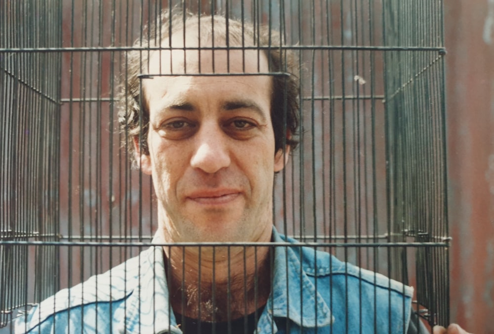 Un hombre con una camisa azul está detrás de una jaula