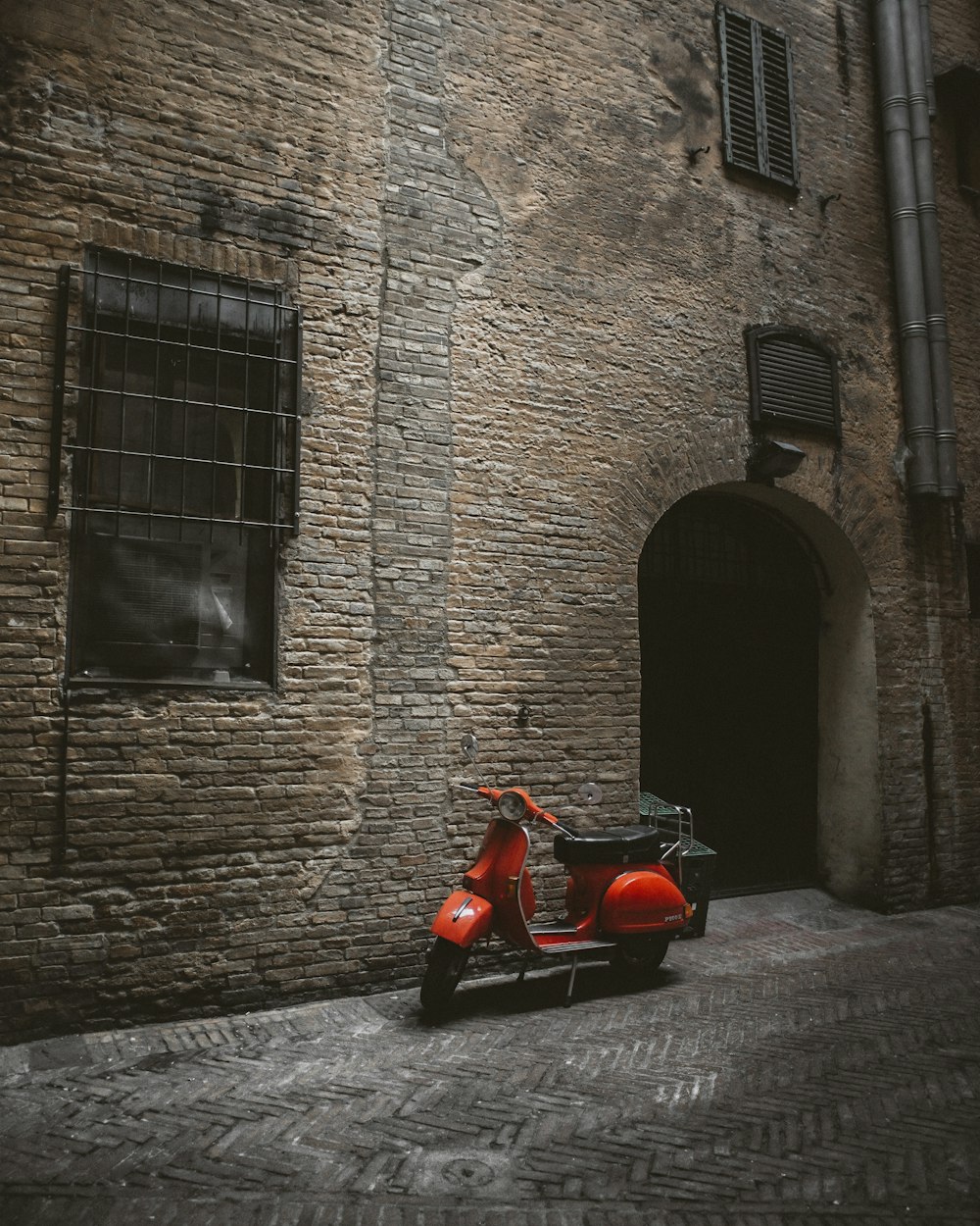 a red scooter parked in front of a brick building