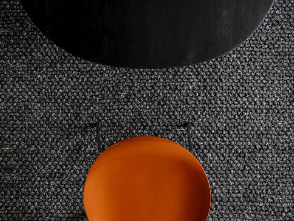 Ein orangefarbener Teller sitzt auf einem schwarzen Tisch