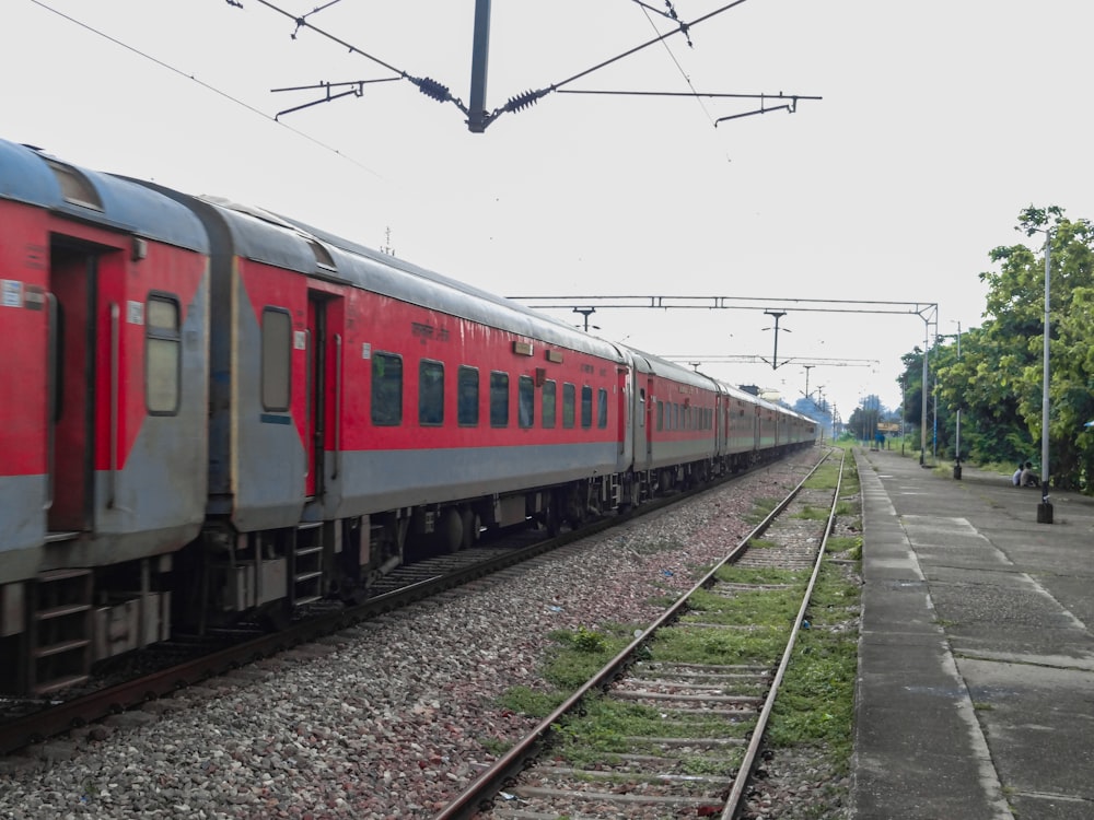 a red train traveling down train tracks next to a forest