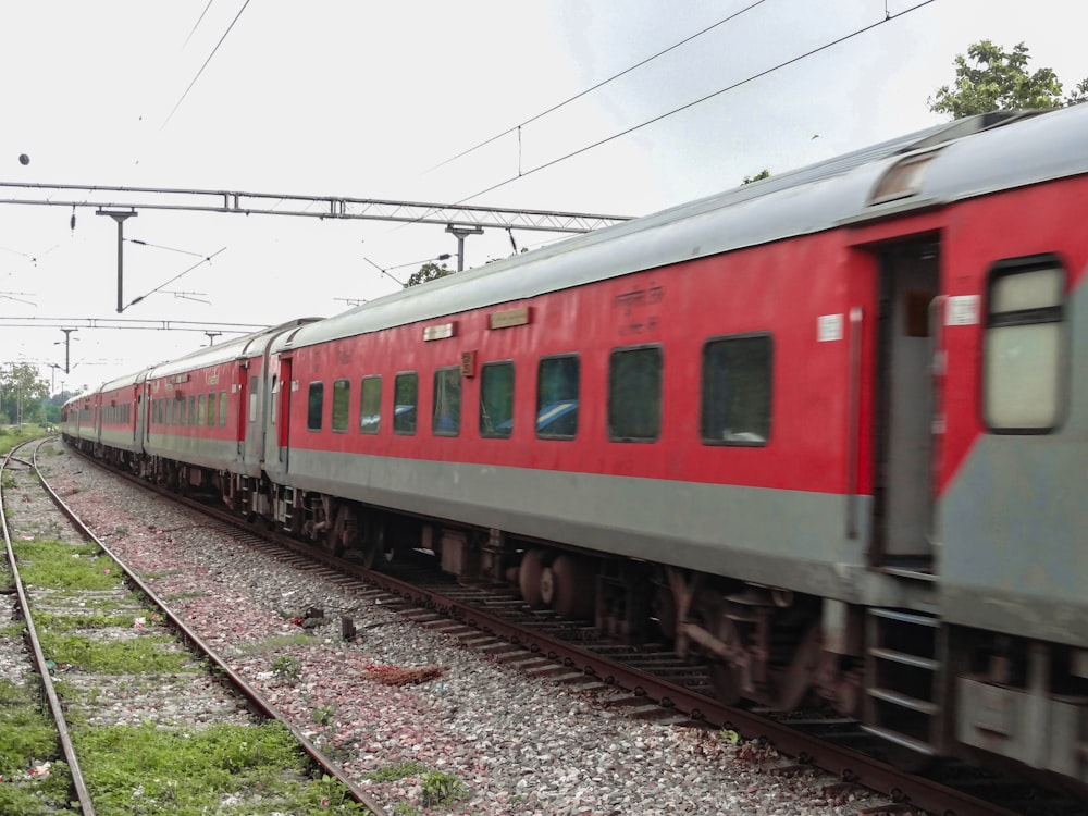 a red train traveling down train tracks next to a forest