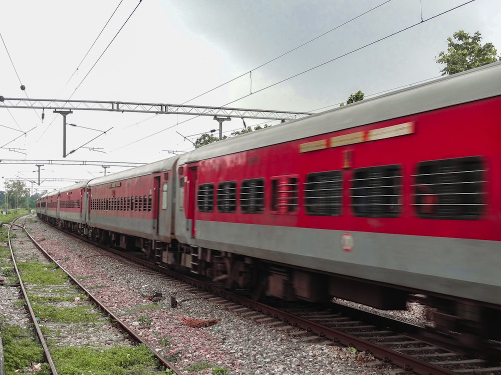 a red train traveling down train tracks next to a forest