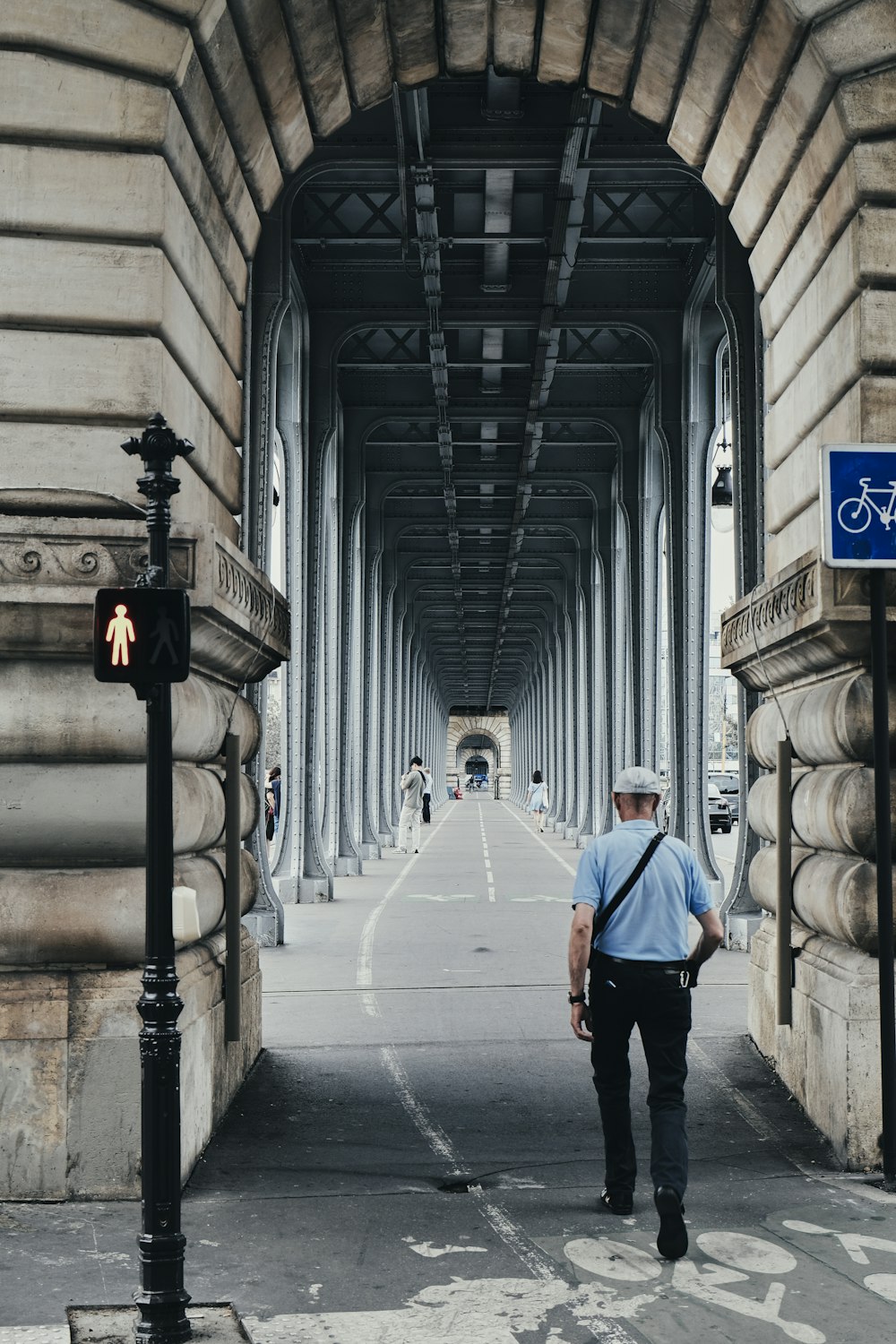 a man walking down a street under a bridge