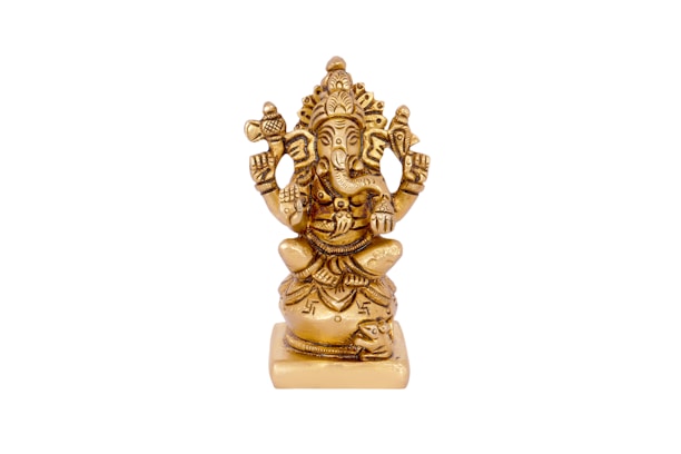 A golden statue of Ganesha, a Hindu deity, featuring detailed carvings and intricate designs. The figure is seated, with an elephant head and multiple arms holding various symbolic objects. The craftsmanship displays a high level of intricacy and cultural significance.