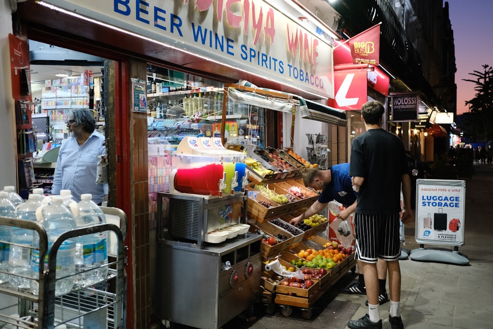 a man standing in front of a store filled with bottles of wine