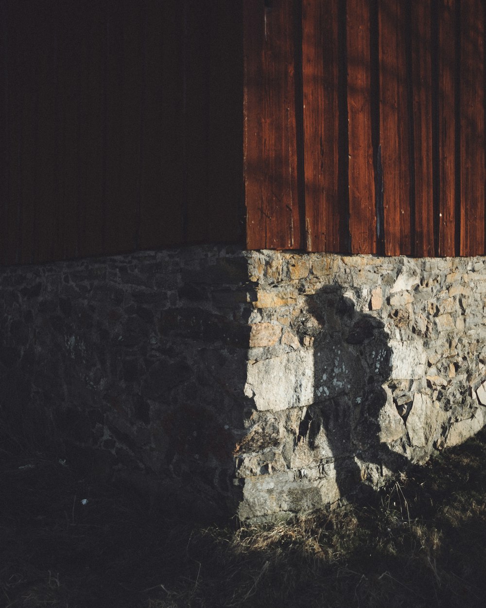 a shadow of a person standing next to a stone wall