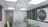 A modern conference room featuring a large table with microphones and green chairs. The room is well-lit with recessed ceiling lights and has dark window blinds. There are potted plants adding greenery, and a sign on the wall reads 'Re-Visitation Mandate' with a microphone graphic.