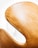 A close-up view of a sleek, curved chair with a light tan, leather-like texture, highlighting its elegant design against a bright white background.