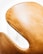 A close-up view of a sleek, curved chair with a light tan, leather-like texture, highlighting its elegant design against a bright white background.