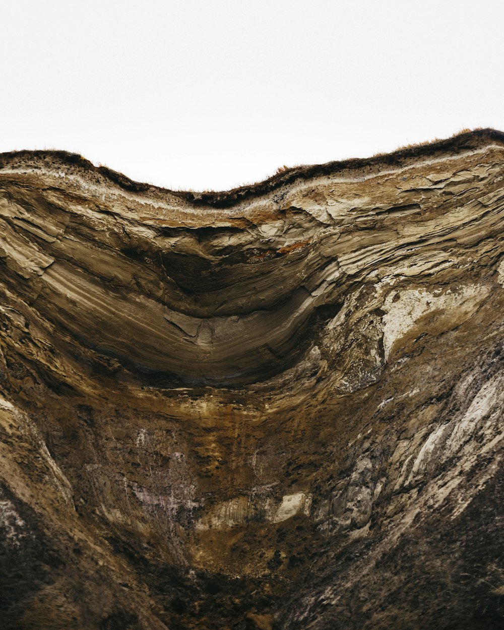 a large rock formation with a white sky in the background