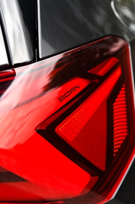 A close-up view of a car's taillight, featuring bold red and black geometric patterns, with the word 'BORN' inscribed in black lettering.