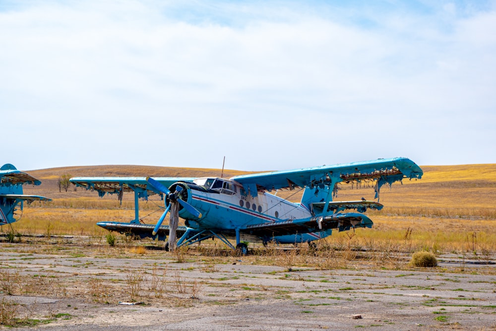 a small blue airplane sitting on top of a dry grass field