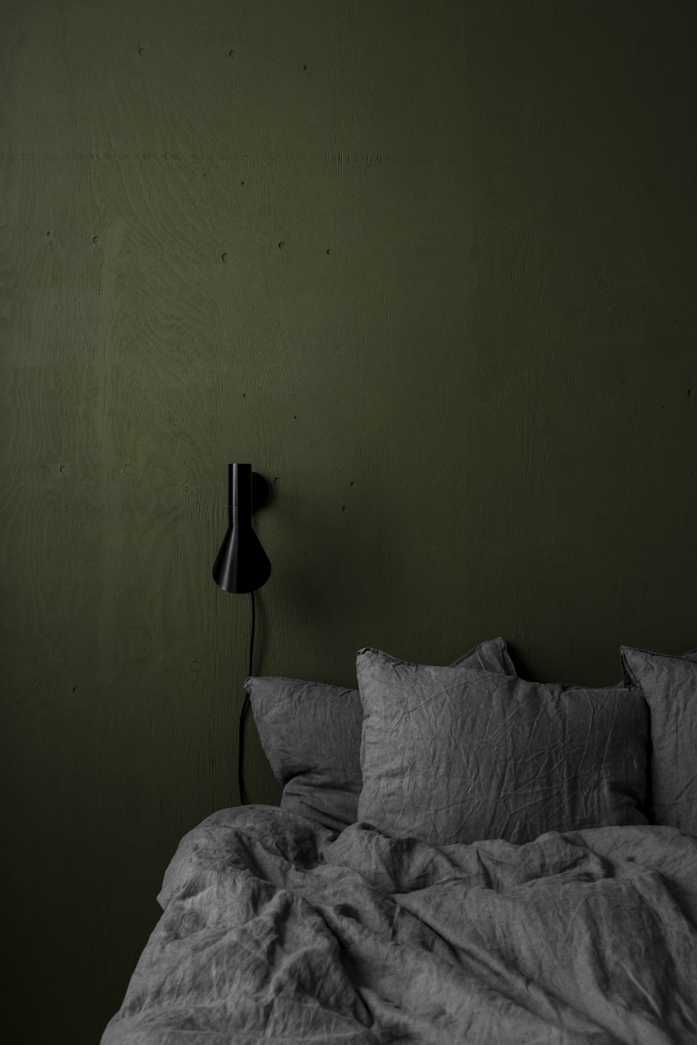 Ein Schwarz-Weiß-Foto eines Bettes in einem dunklen Raum