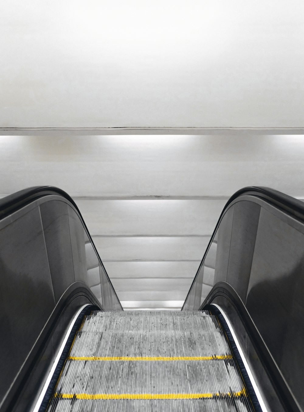 an escalator with a yellow line going down it