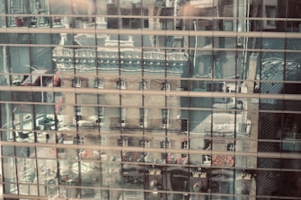 a building is reflected in the windows of another building