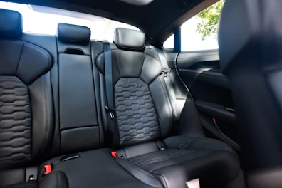 A compact handheld vacuum being used to clean car seats.
