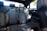 The interior of a modern car displaying the rear passenger seats. The seats are upholstered in black leather with a textured pattern in the center. The car appears to be clean and well-maintained, with the seat belts properly arranged.