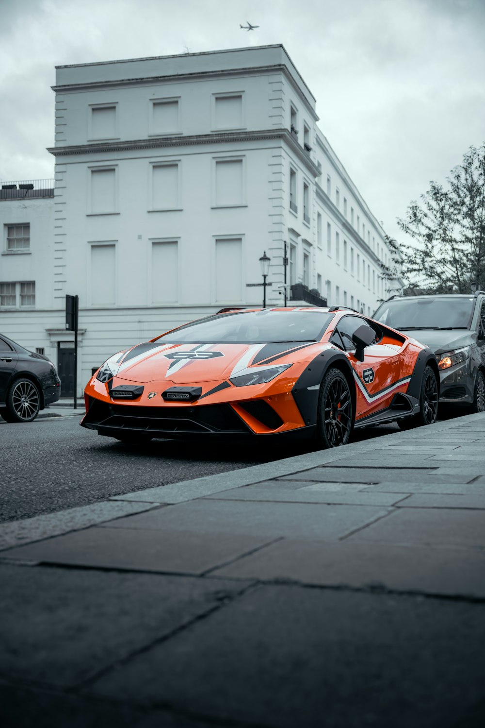 an orange sports car parked on the side of the road