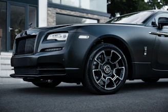 a black rolls royce parked in front of a building